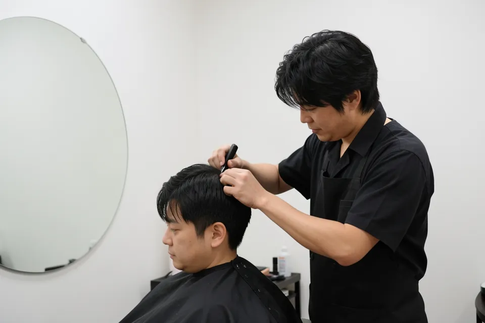 A hairdresser trimming a client's hair in a small Tokyo salon